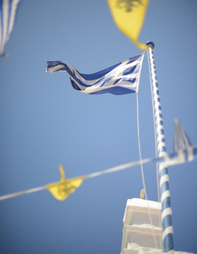 a greek flag flies above a church in mykonos